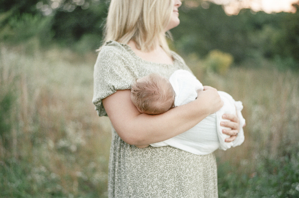 Film scan of an infant's head in the bend of his mothers arms as she states into the sunset