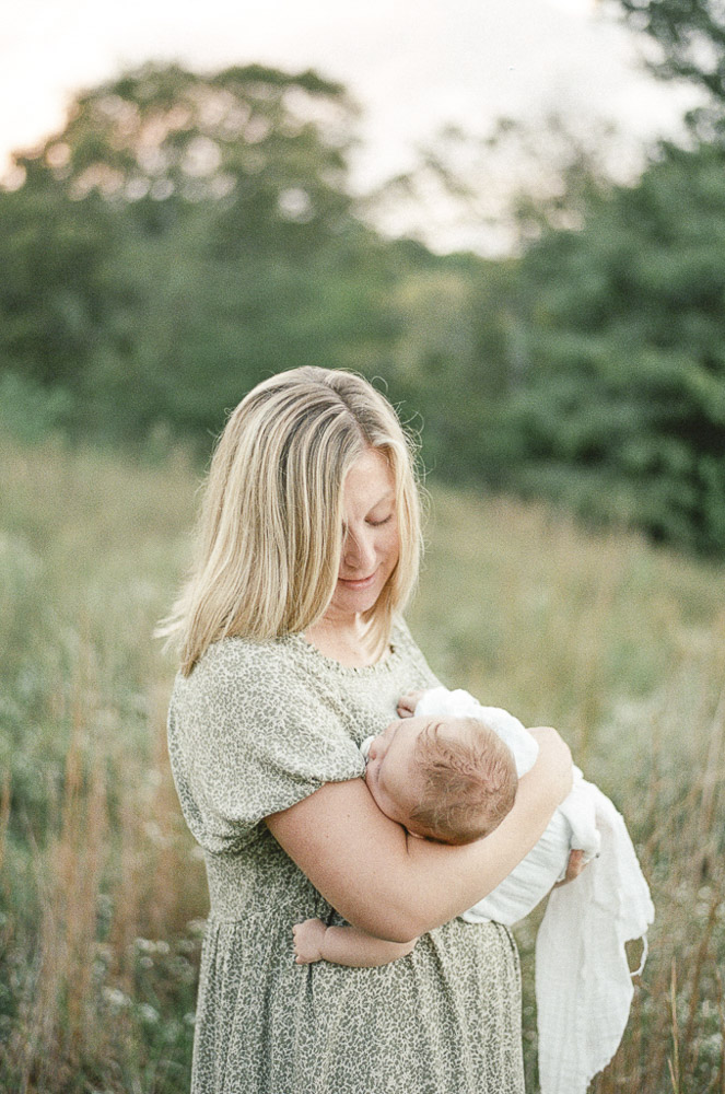 Film scan with grain of a mother rocking her infant in a wildflower field