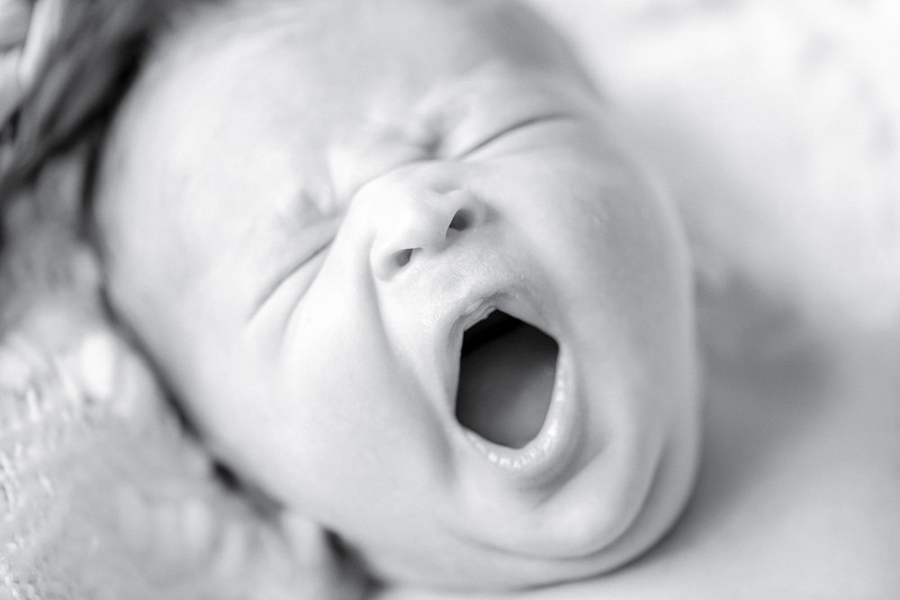 Black and white image of a newborn yawning