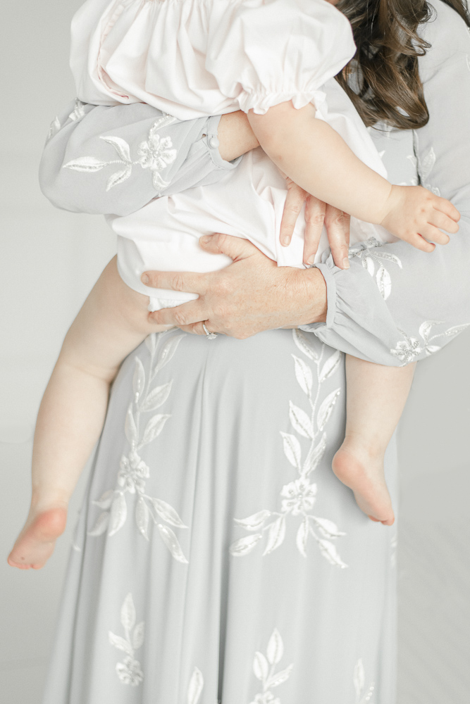 A mother's hands hold her young daughter on her hip