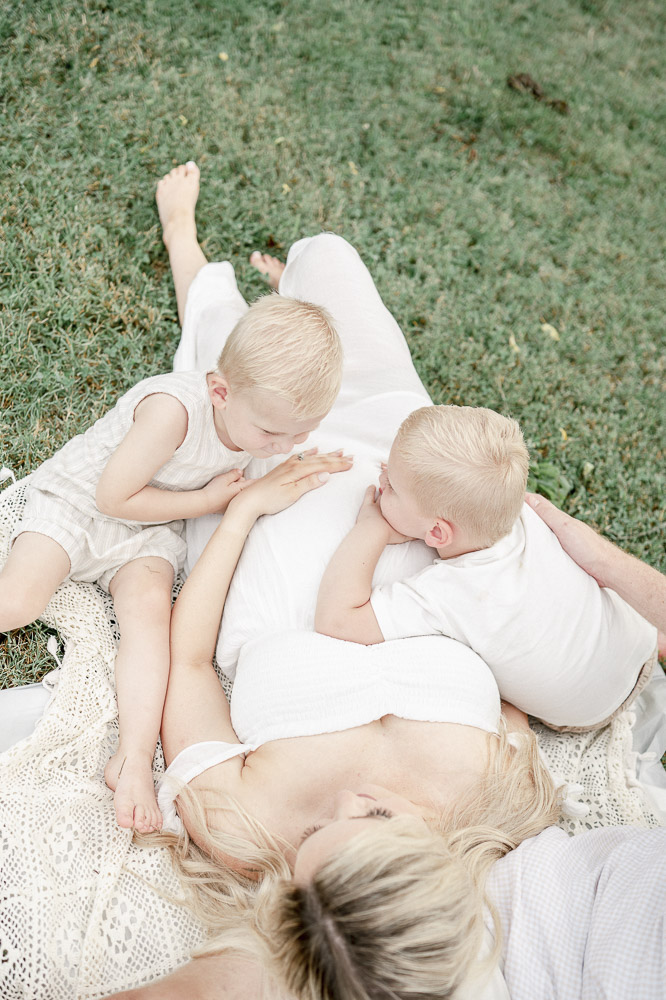 Two young boys lay across their mother's pregnant stomach by Franklin TN Maternity photographer Kristie Lloyd.