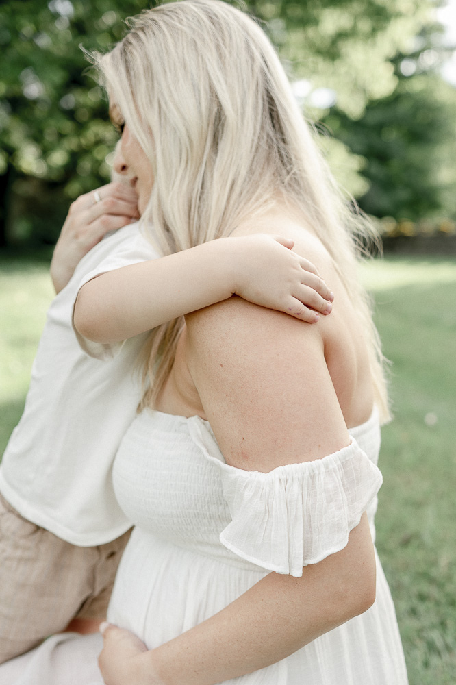 A young boy's hand rests on his mother's should while they hug by Franklin TN Maternity photographer Kristie Lloyd.