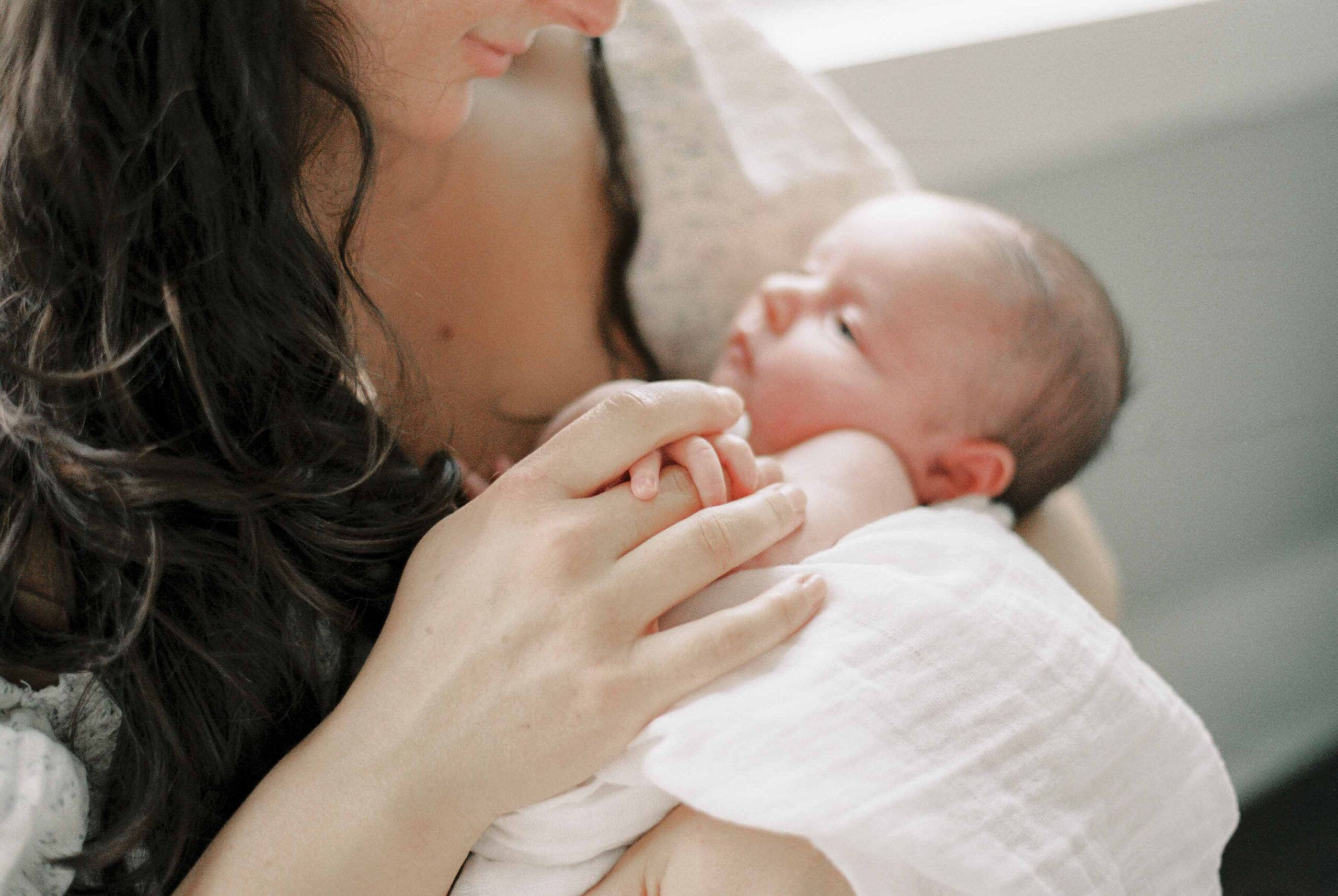 Detail photo of a mother holding a newborn's fingers