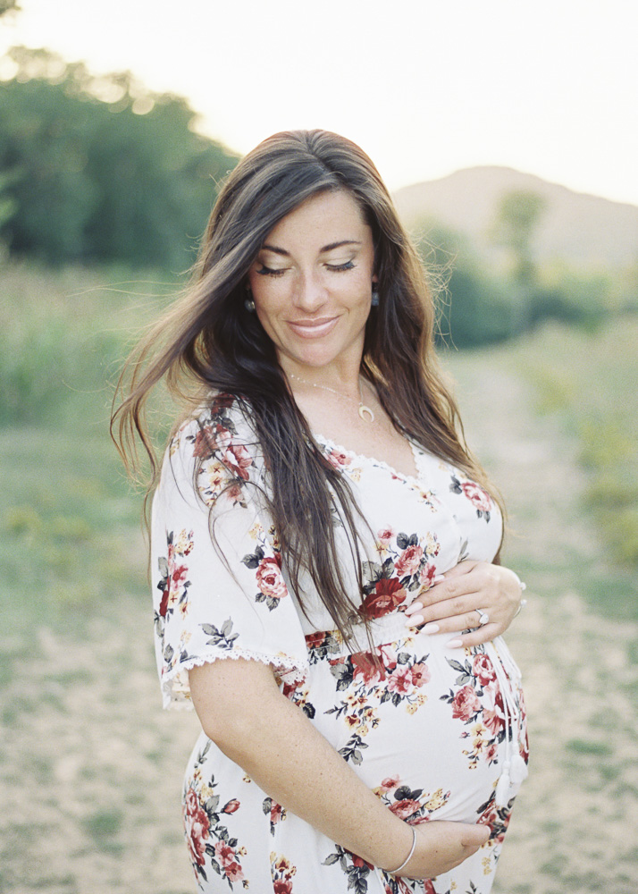 Pregnant woman smiles over her shoulder as her hair is tousled by the wind
