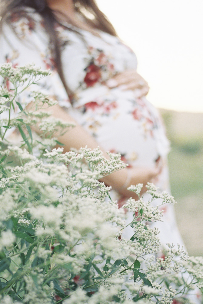 White flowers in front of a blurry pregnant belly