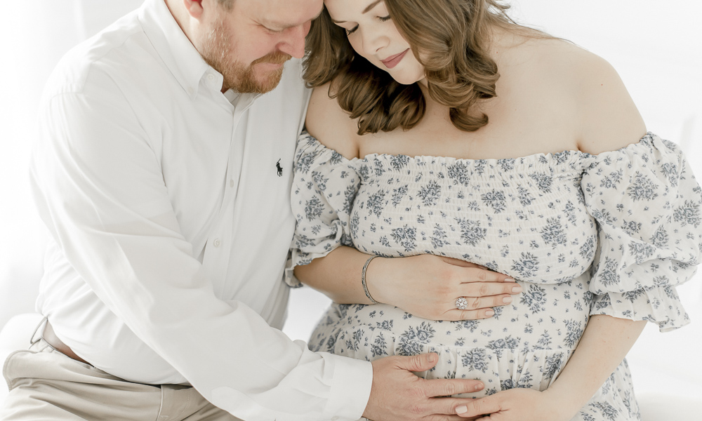 A husband places his hand on his pregnant wife's stomach