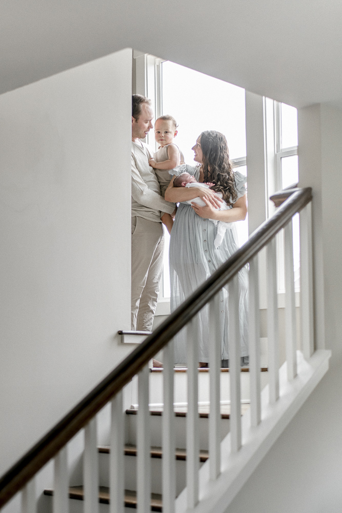 A family stands at the top of a stairwell with a newborn and a toddler