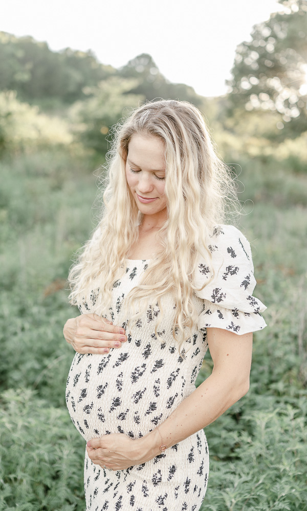 outdoor maternity photo of a woman in a black and white dress holding her stomach