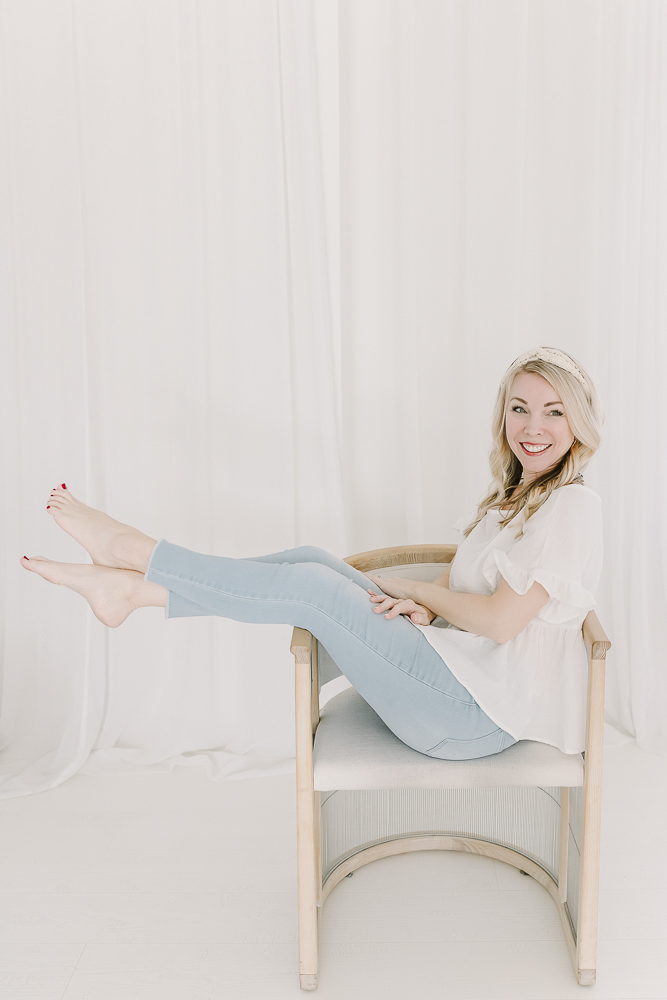 Nashville baby photographer Kristie Lloyd sits in a chair with her feet in the air