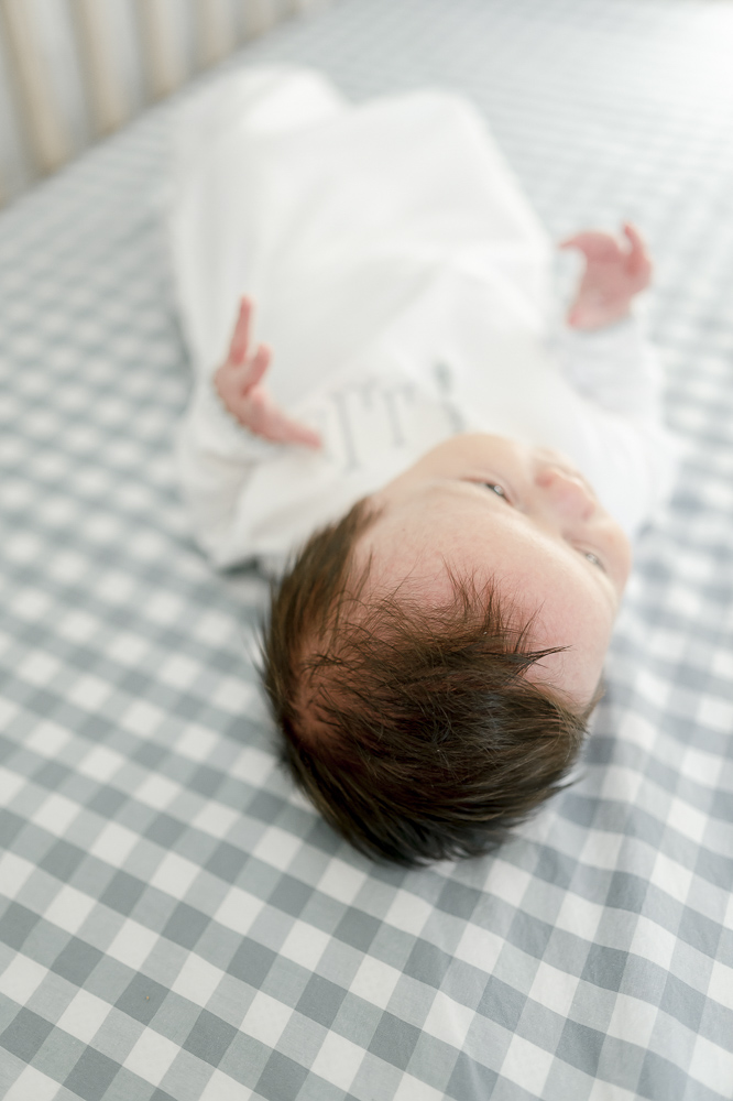 Newborn baby with a head full of dark brown hair for his newborn photos at home in his Thompson's Station nursery