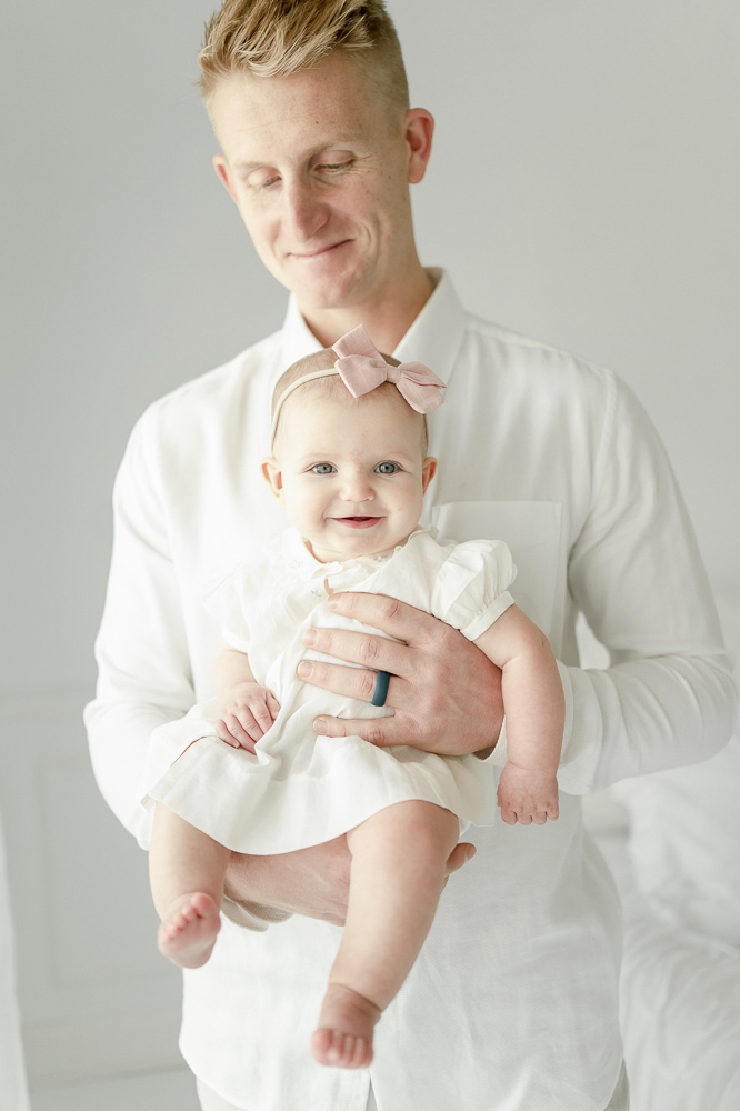 A father holds his 6 month old baby girl in Nashville baby photographer Kristie Lloyd's studio
