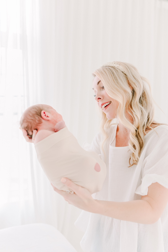Newborn photographer holds a baby wrapped in the Swaddle Pro