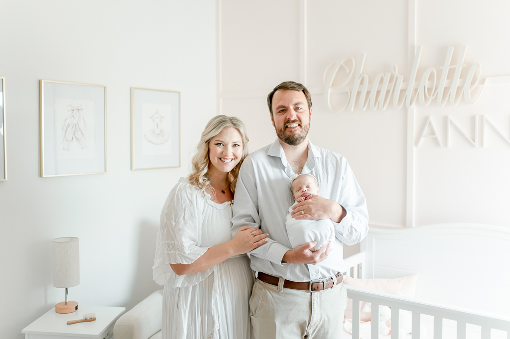 A new mom and dad smile as they hold their newborn in their Brentwood Tennessee home's nursery  by Brentwood newborn photographer Kristie Lloyd.