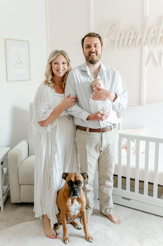 Family smiles holding their newborn with their dog sitting at their feet for a family portrait  by Brentwood newborn photographer Kristie Lloyd..
