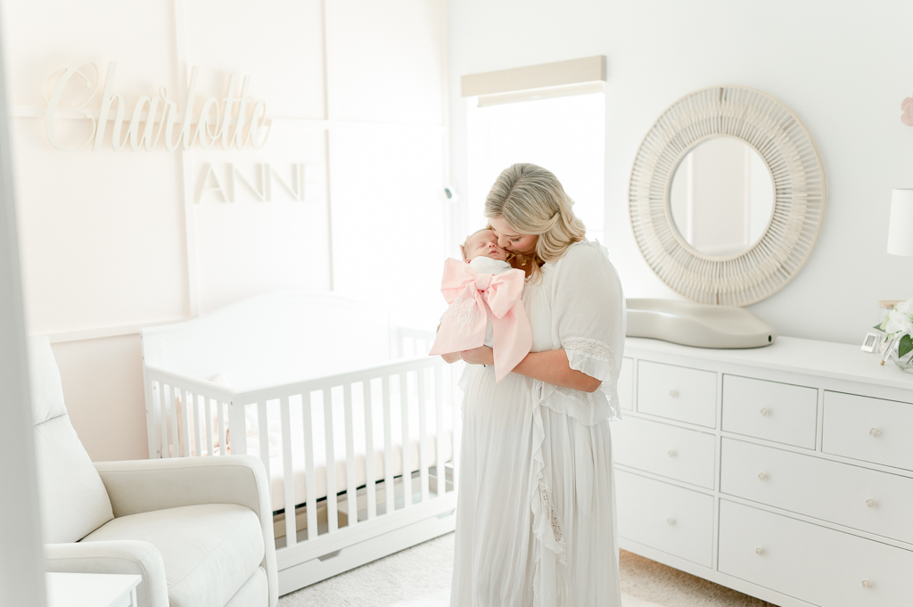 A new mother holds her baby in a Nashville nursery by Brentwood newborn photographer Kristie Lloyd.