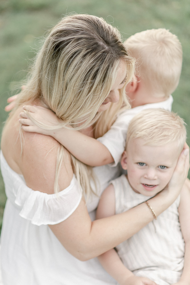 A soft image looking downward onto a mother hugging her two sons by Franklin TN Maternity photographer Kristie Lloyd.