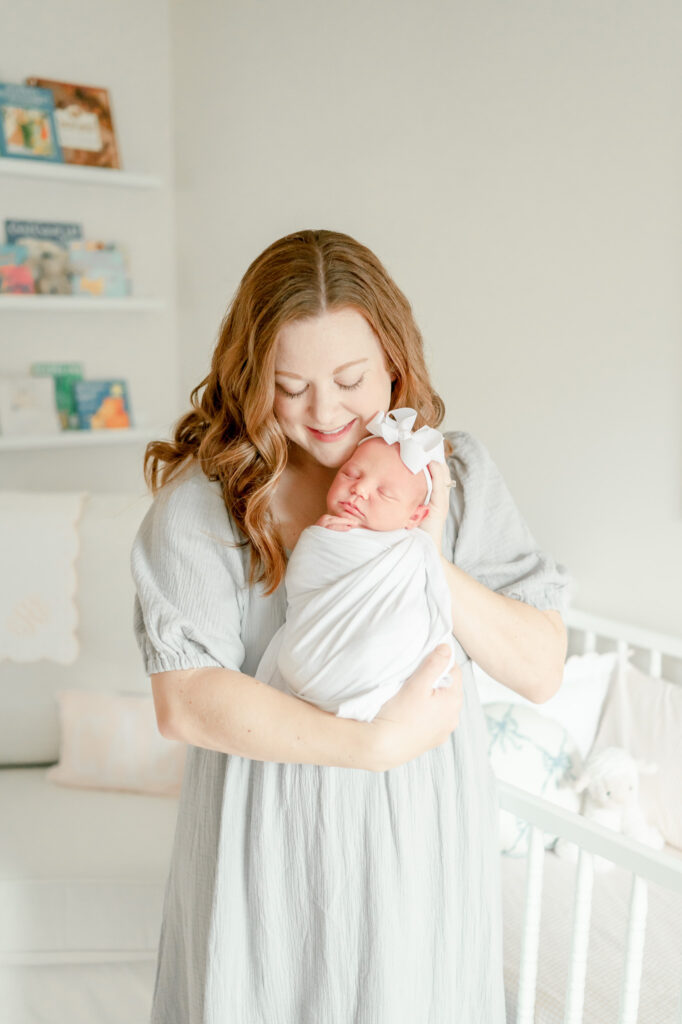 A red haired mother smiles down at her sleeping newborn during her session with nashville newborn photographer kristie lloyd