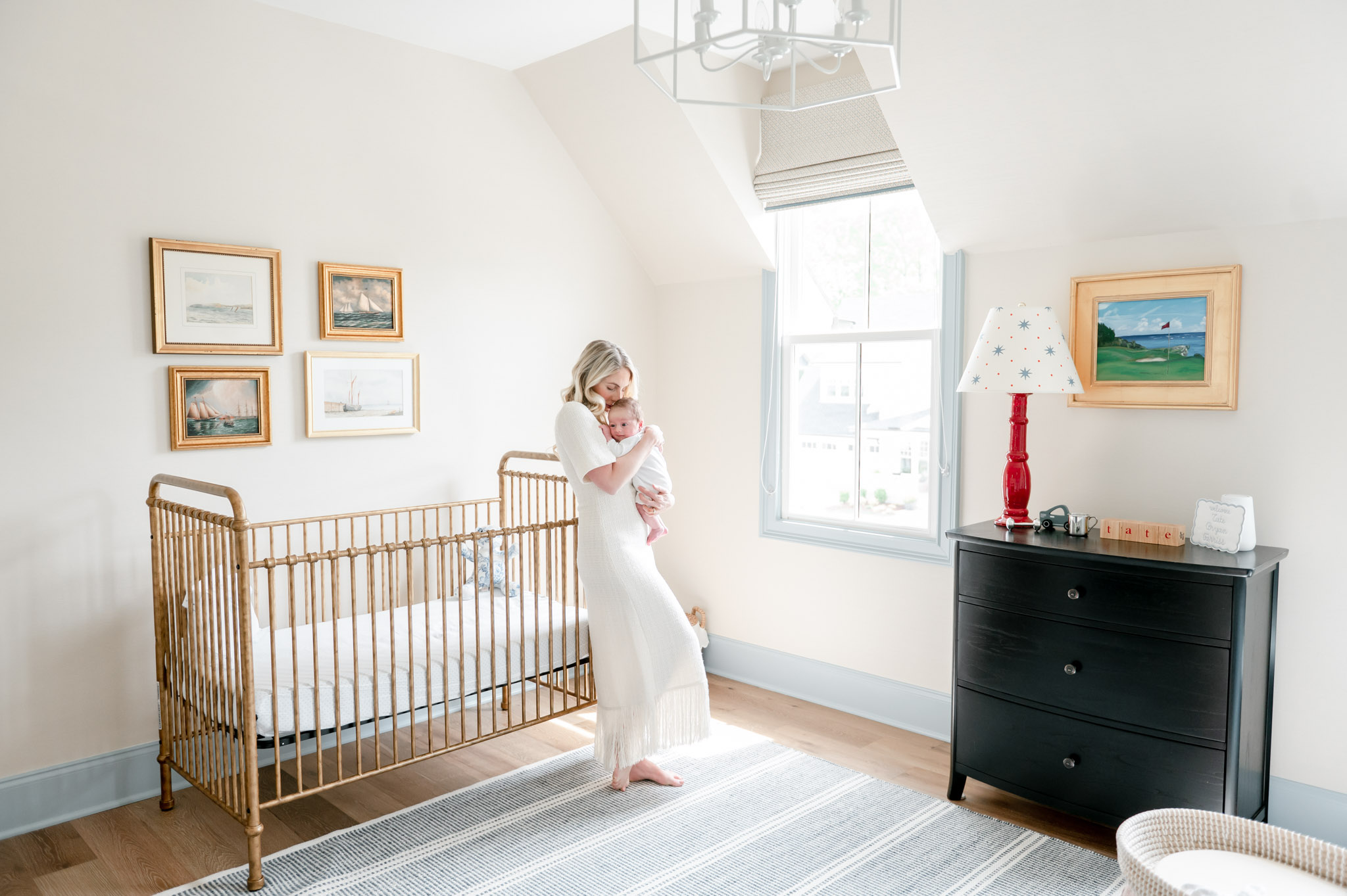 Nursery inspiration : a mom holds her baby as she leans on a gold crib