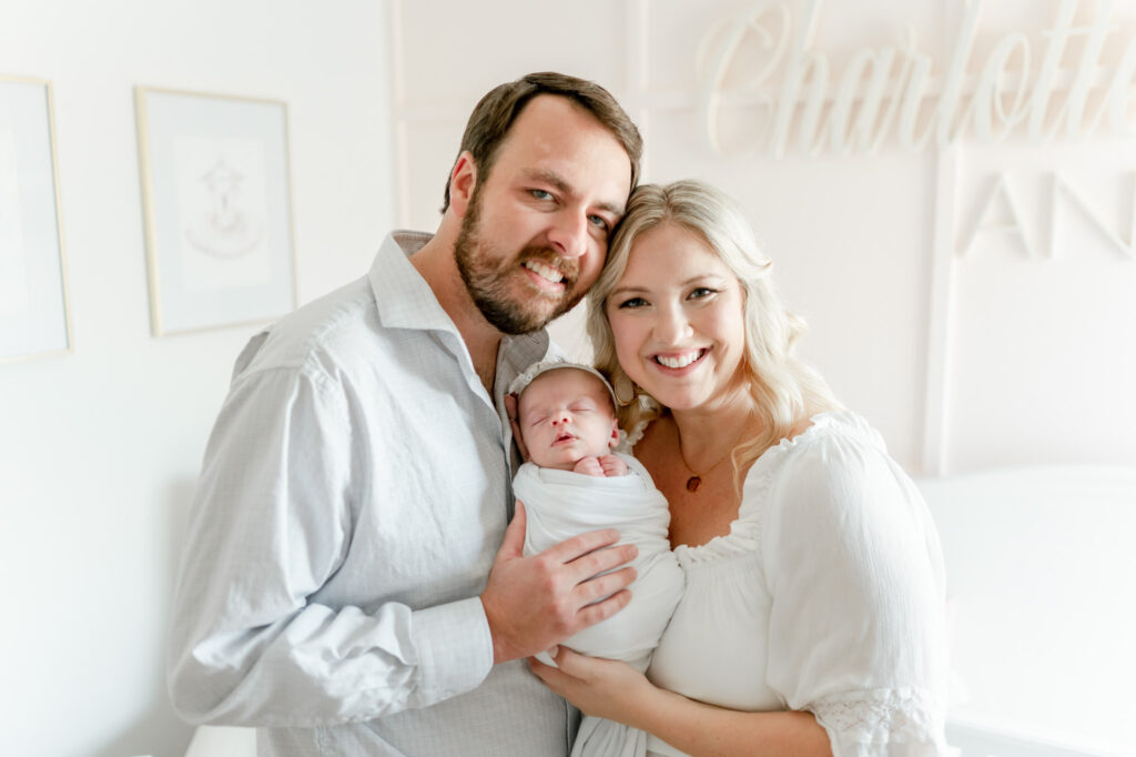 New parents hold their baby girl in a pink nursery