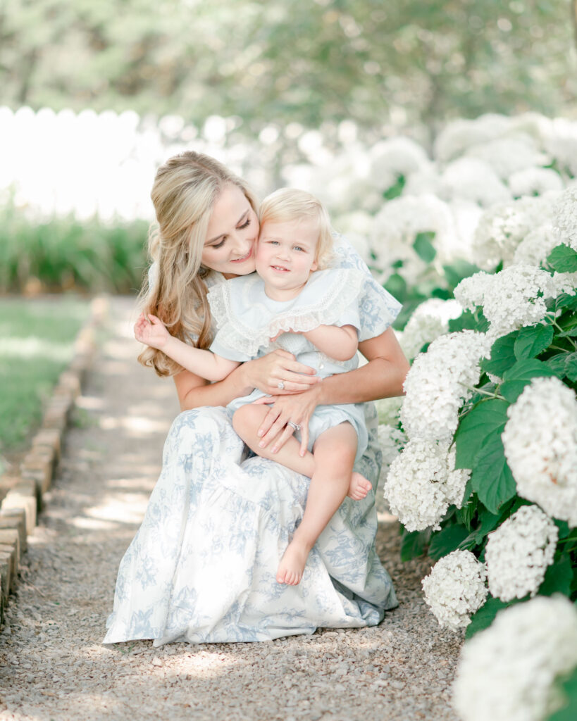 A mother hugs her 2 year old son in front of white hydrangeas by Franklin TN photographer Kristie Lloyd