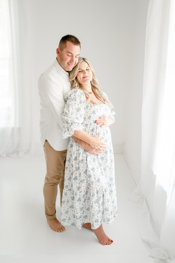  A man hugs his pregnant wife during studio maternity photos.