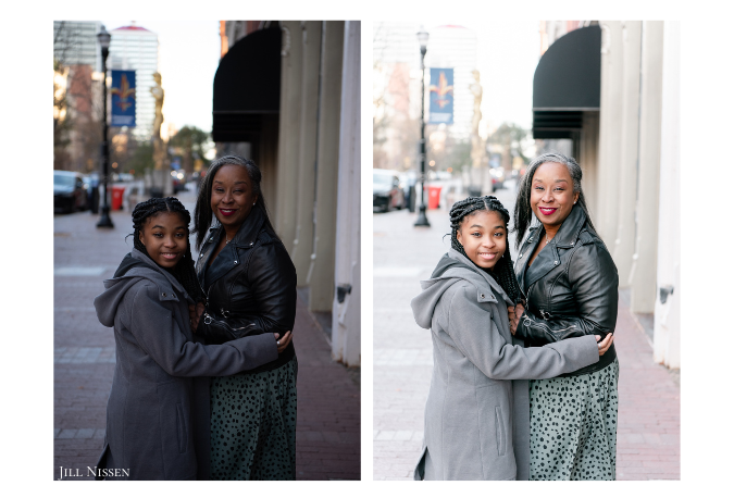 An African American mother and daughter hug in the streets of a city.