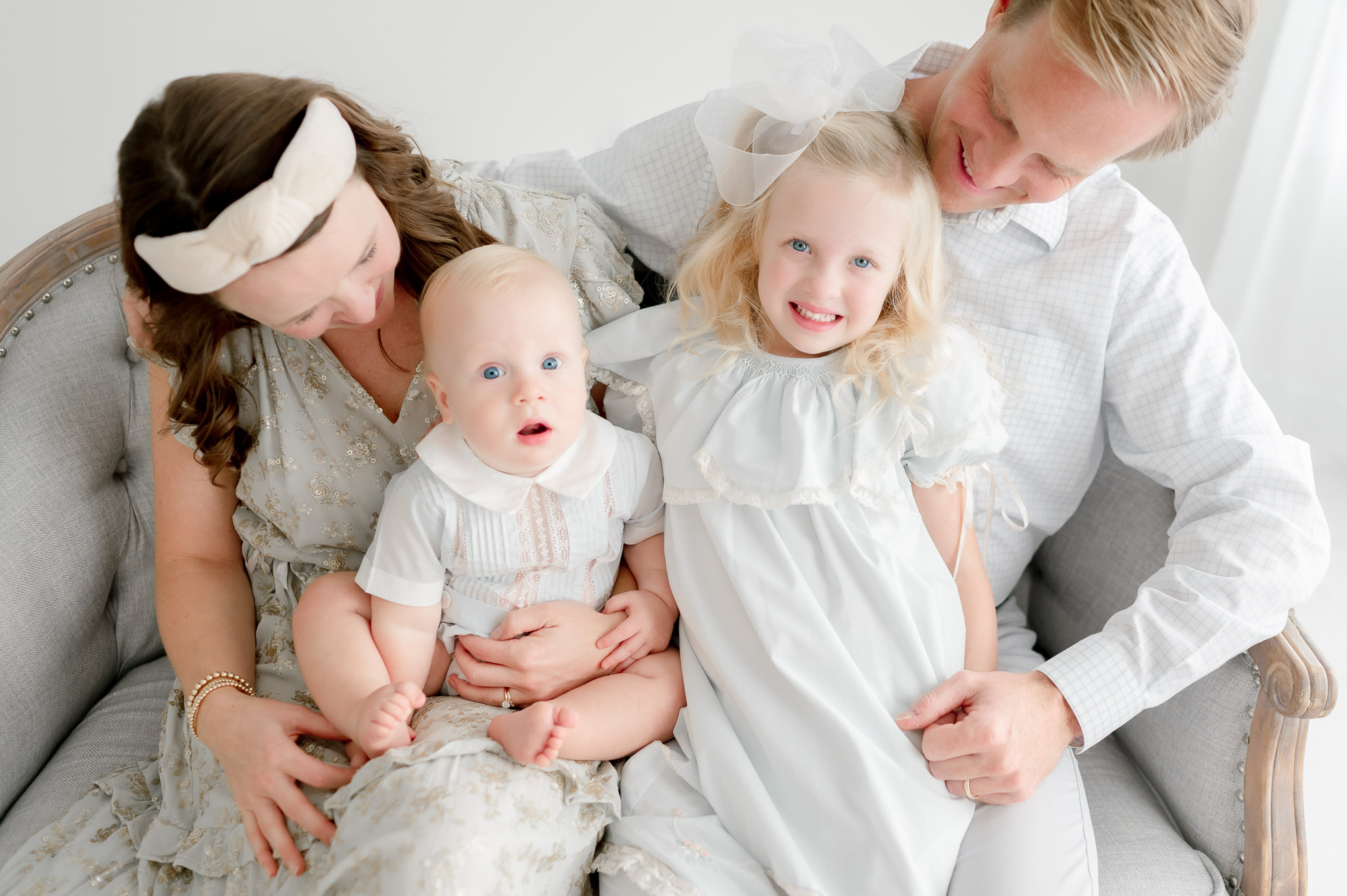 Brother and sister smile as their parents hold them