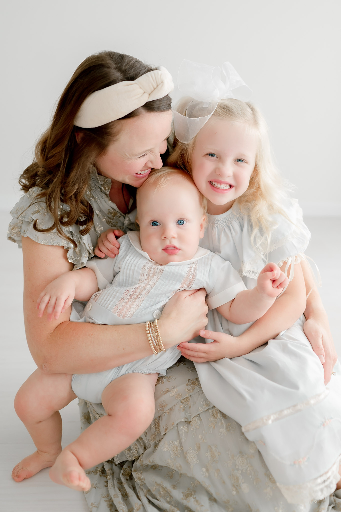 A mother hugs her baby and toddler