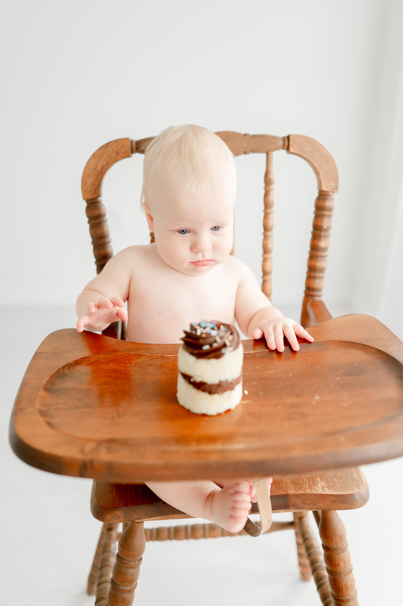 Baby stares at a cupcake sitting in a high chair