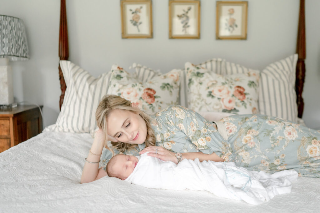 A mother lays on the bed with her newborn