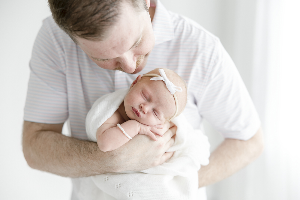A dad smiles down as he holds his newborn baby