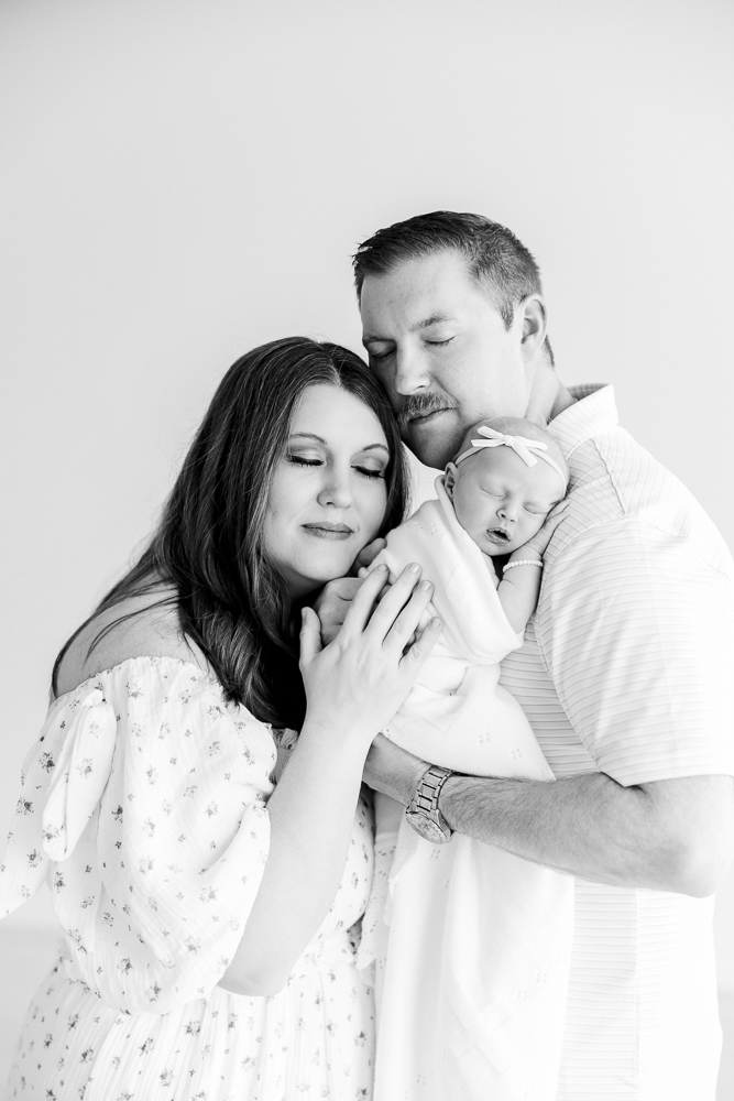 black and white image of a mom and dad holding their newborn baby