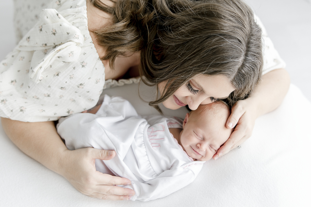 A mother holds her newborn baby who is smiling as she sleeps